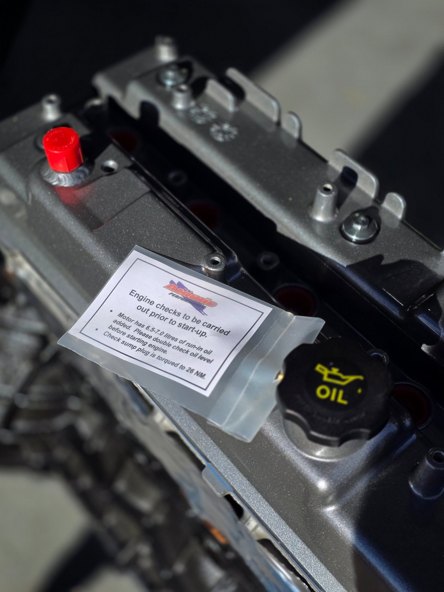 atomic label and tag on grey engine rocker cover with black oil cap and red cap