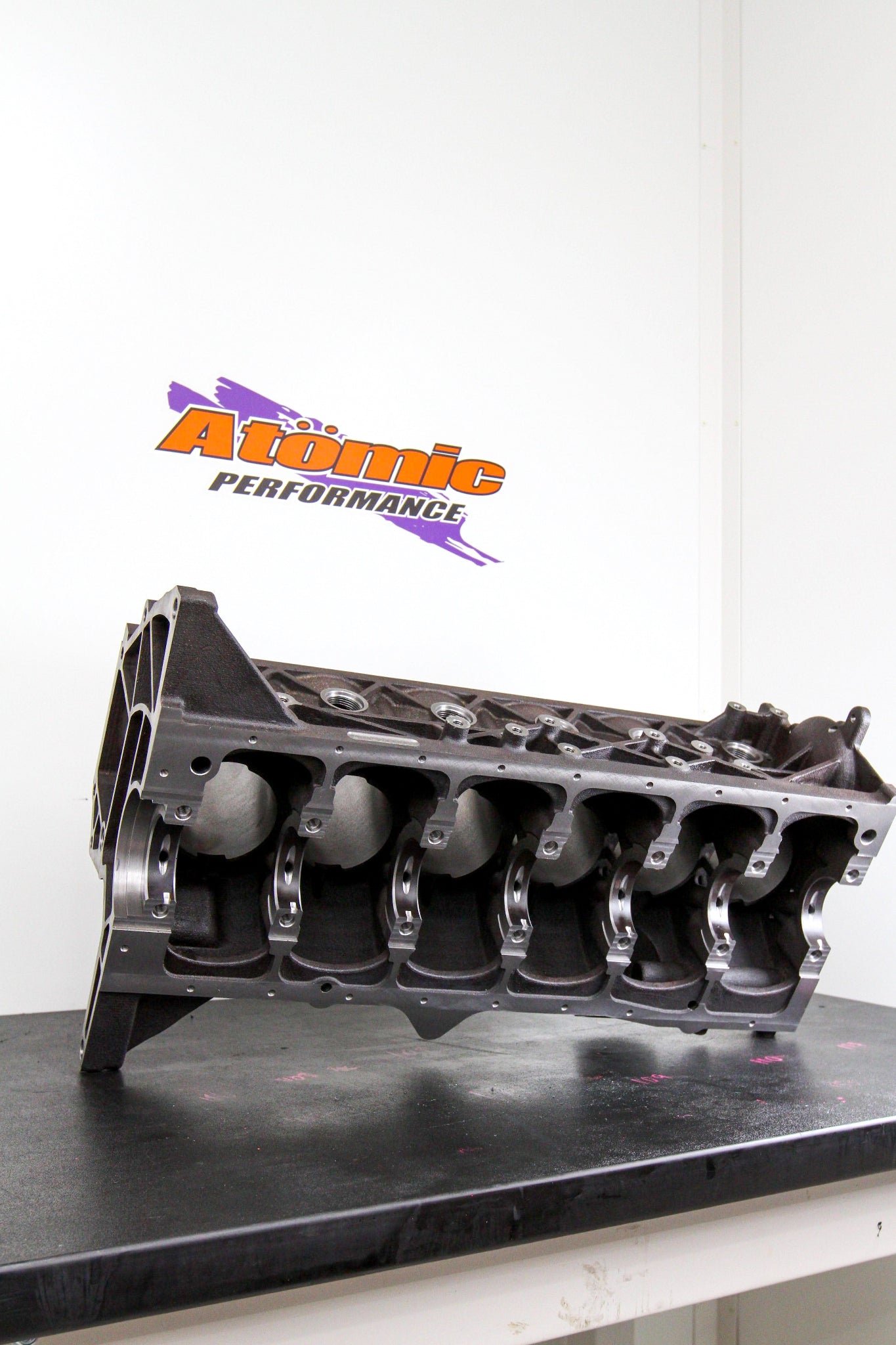 Engine block on a stand with 'Atomic Performance' logo in the background