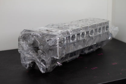 engine cylinder head wrapped in plastic on a black bench with a white background
